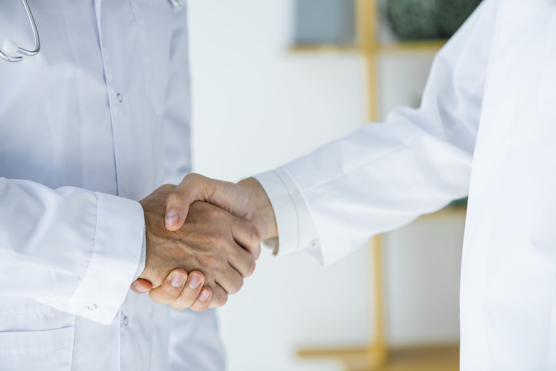 Two doctors in white coats shaking hands in a hospital setting, symbolizing collaboration and professionalism in healthcare Two doctors in white coats shaking hands in a hospital setting, symbolizing collaboration and professionalism in healthcare